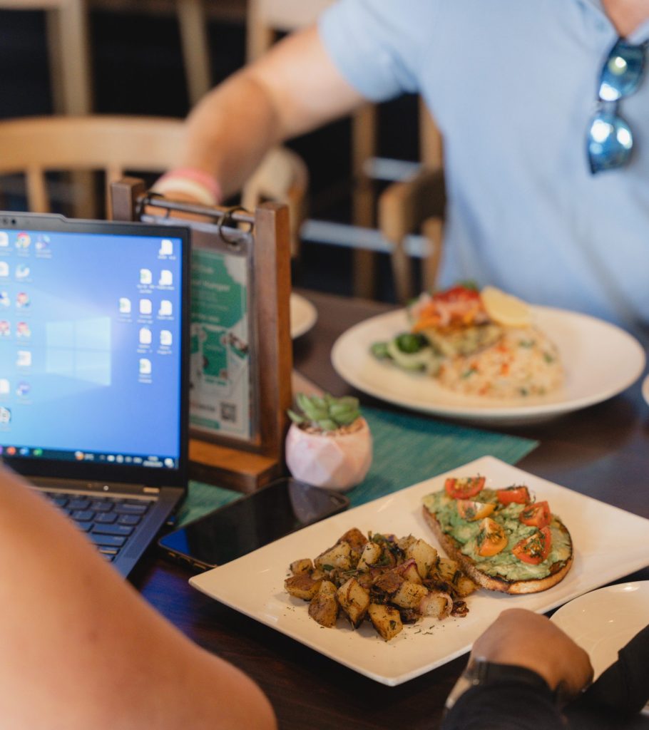 People enjoying food while working on laptops at a Bite Club restaurant in Grand Cayman.